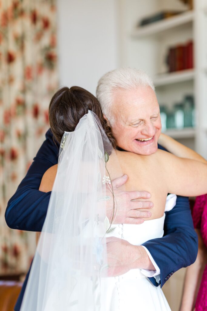 Bride and Brides Dad hugging during a joyful first look moment captured from a second photographers perspective. 