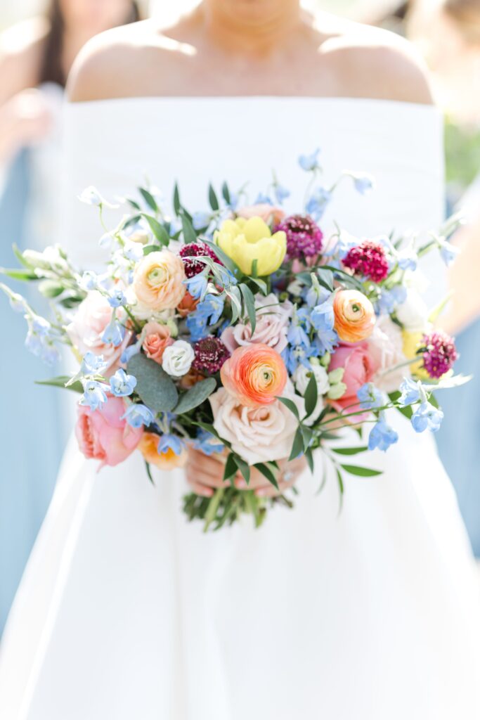 Bride holding her floral bouquet on her wedding day captured from a second photographers perspective. 