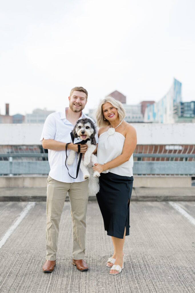 Engaged couple posing with their dog.