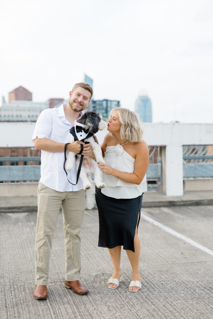 Engaged couple posing with their dog.