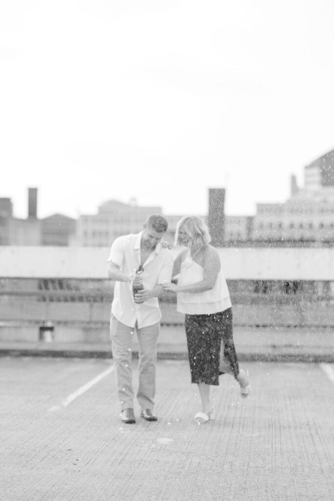 Engaged couple popping champagne on the rooftop garage of Hotel Covington.