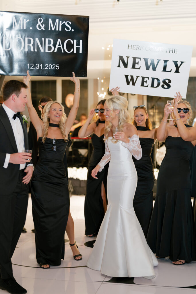 bride and groom enter wedding reception with wedding party holding celebratory signs